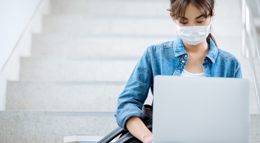 Eine Studentin mit Maske am Laptop.