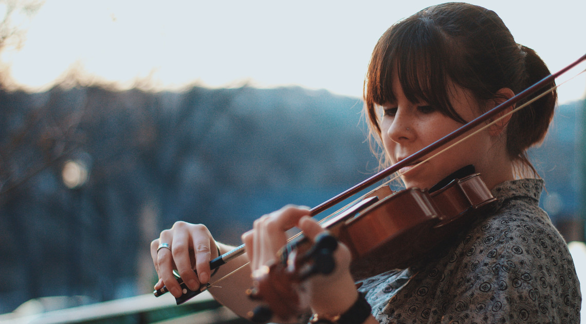 Eine Frau spielt im Freien Geige.