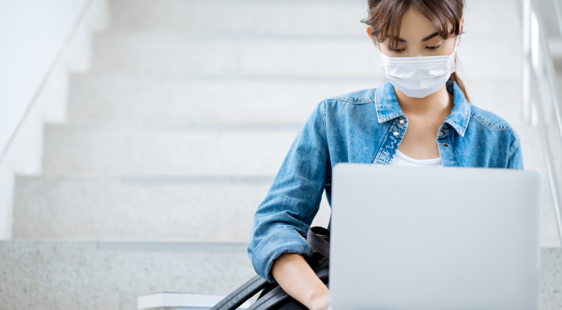 Eine Studentin mit Maske am Laptop.