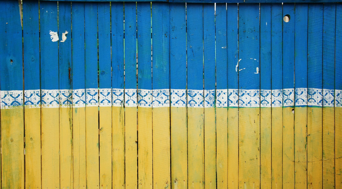 Ein Bauzaun in Kiew in den Farben der Ukraine (Foto: Tina Hartung/Unsplash)